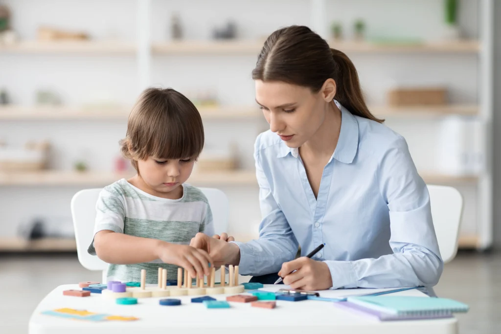 Therapist guiding young boy during occupational therapy session – developing coordination and learning skills