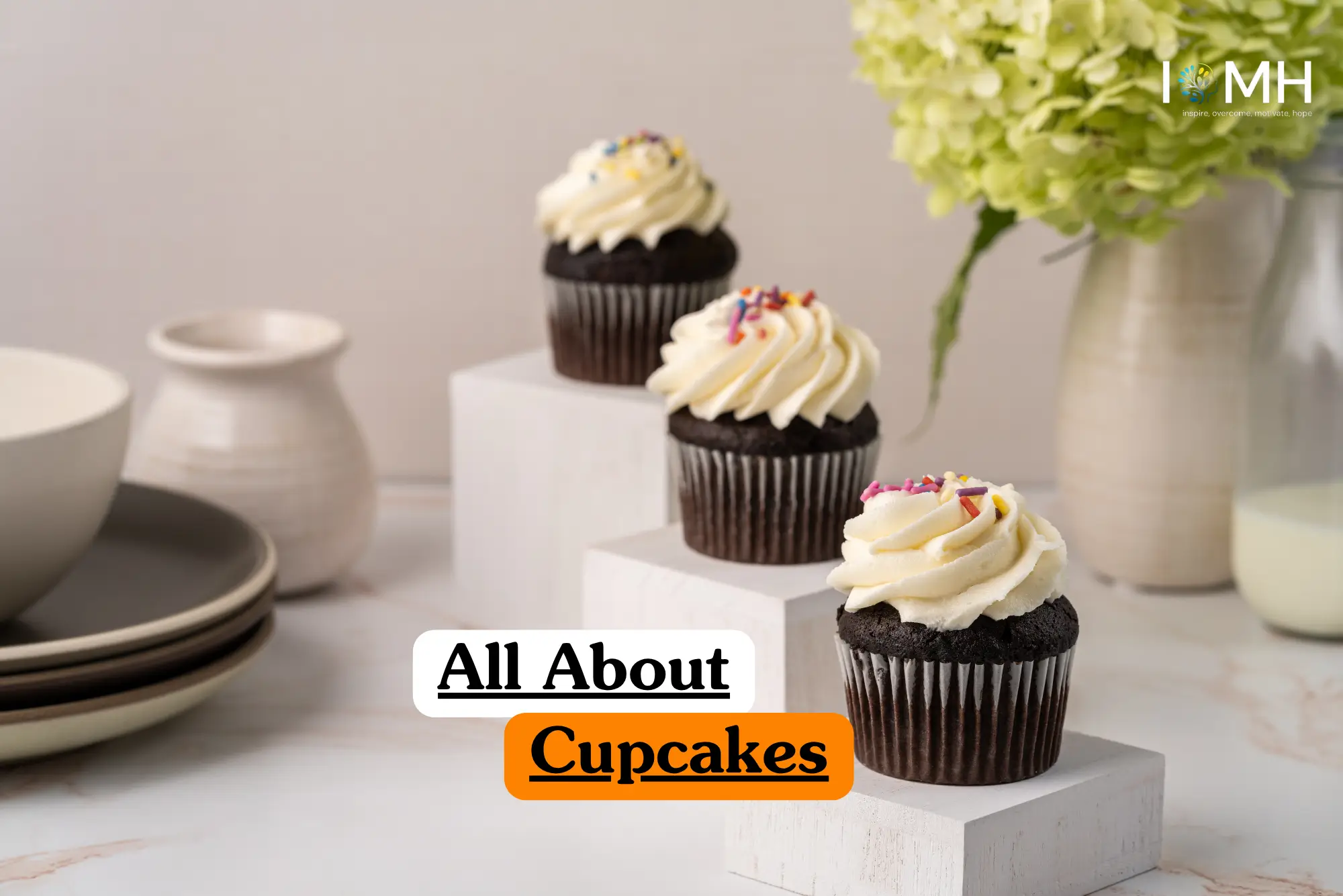 Theoretical food science and pastry arts training banner featuring three chocolate cupcakes with white swirl frosting and colorful sprinkles, elegantly arranged on white marble-textured blocks.