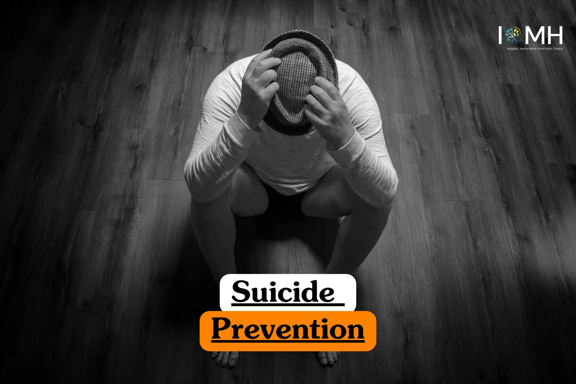 Theoretical mental health awareness and crisis intervention training banner featuring a person in a white long-sleeved shirt sitting on a dark wood floor, head lowered and hands clutching a hat, symbolizing the psychological study of emotional distress and prevention.