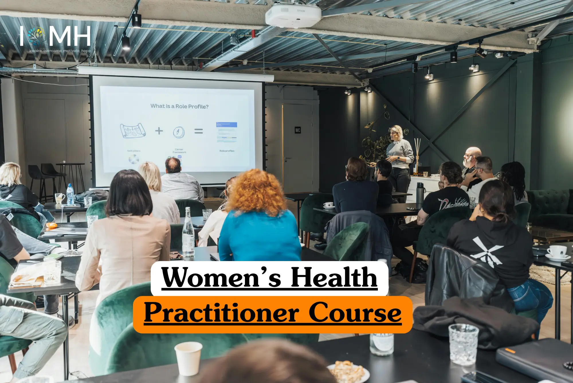 Theoretical healthcare and professional development training banner featuring a diverse group of adults in a seminar setting, watching a presentation on "What is a Role Profile?" displayed on a projector screen, representing the study of career frameworks and practitioner roles in women's health.