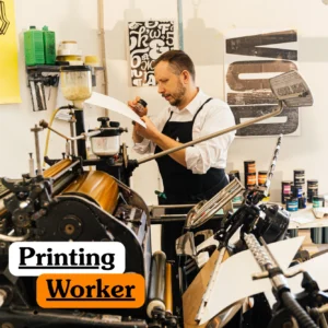 Theoretical industrial arts and commercial printing training banner featuring a professional printer in a black apron meticulously inspecting a printed sheet using a magnifying loupe.