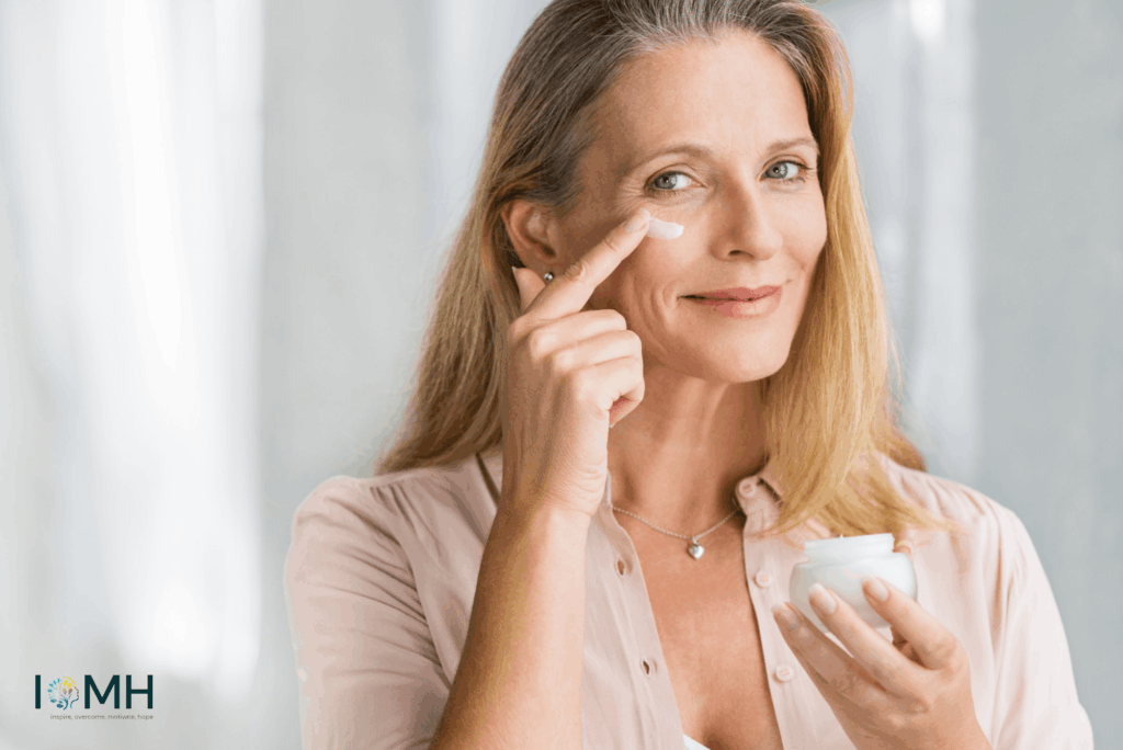 Mature woman applying anti-ageing eye cream under her eye while holding a jar of moisturiser