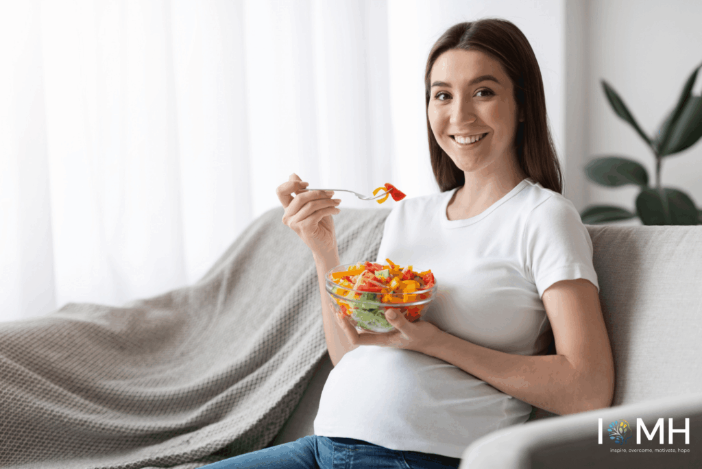 Smiling pregnant woman eating a fresh vegetable salad for healthy pregnancy nutrition