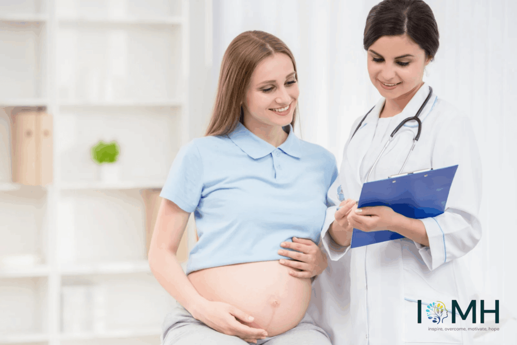 Pregnant woman smiling and holding her baby bump during a prenatal consultation with a female doctor holding a clipboard in a bright clinic – professional pregnancy care guidance