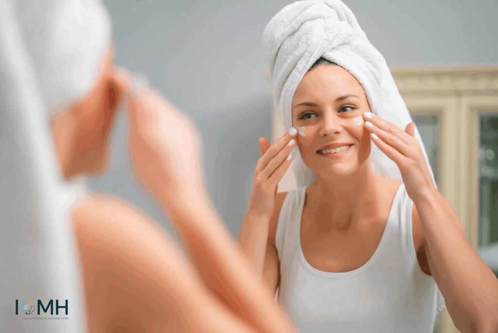 Smiling woman with towel on her head applying moisturising cream to her face in front of a mirror – safe pregnancy skincare and facial care routine