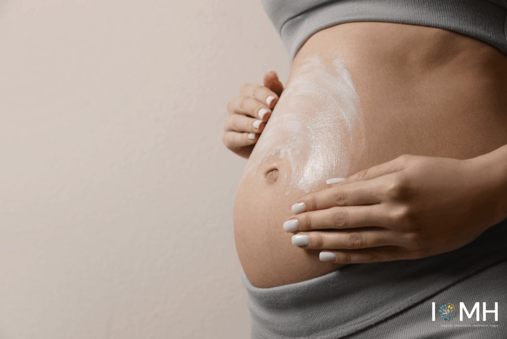 Pregnant woman gently applying moisturizing cream to her growing belly for pregnancy skincare and stretch mark prevention