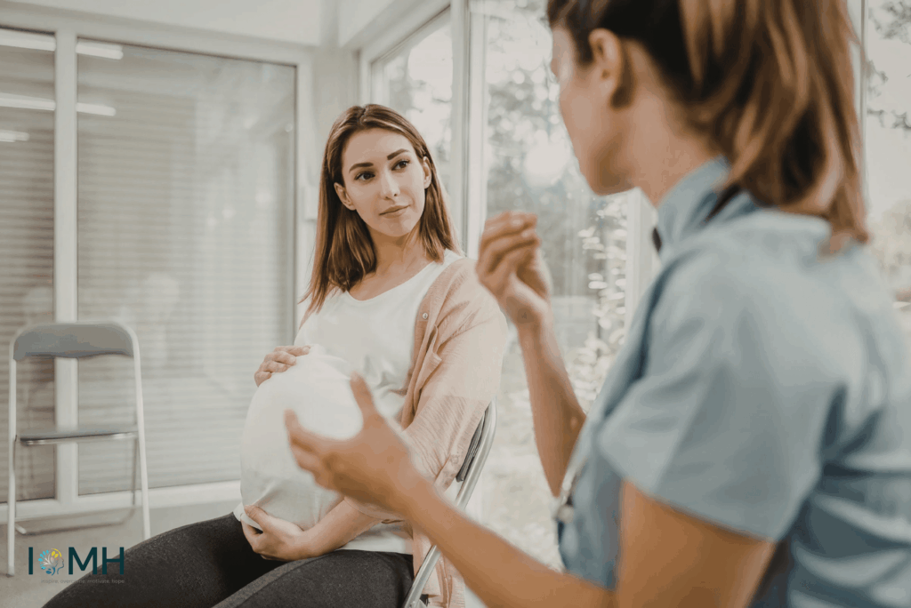 Pregnant woman discussing prenatal care with a doctor or midwife during a pregnancy checkup appointment